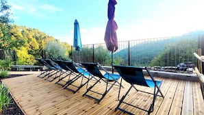 A wooden deck with lounge chairs and a blue umbrella. - Mas de 130m2 en Plein Cœur des Cévennes sur 12 Hectares (Lamelouze)