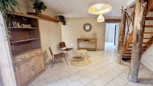 A rustic interior with a wooden staircase, a round table with chairs, a wooden cabinet, and a hanging light fixture. - Mas de 130m2 en Plein Cœur des Cévennes sur 12 Hectares (Lamelouze)