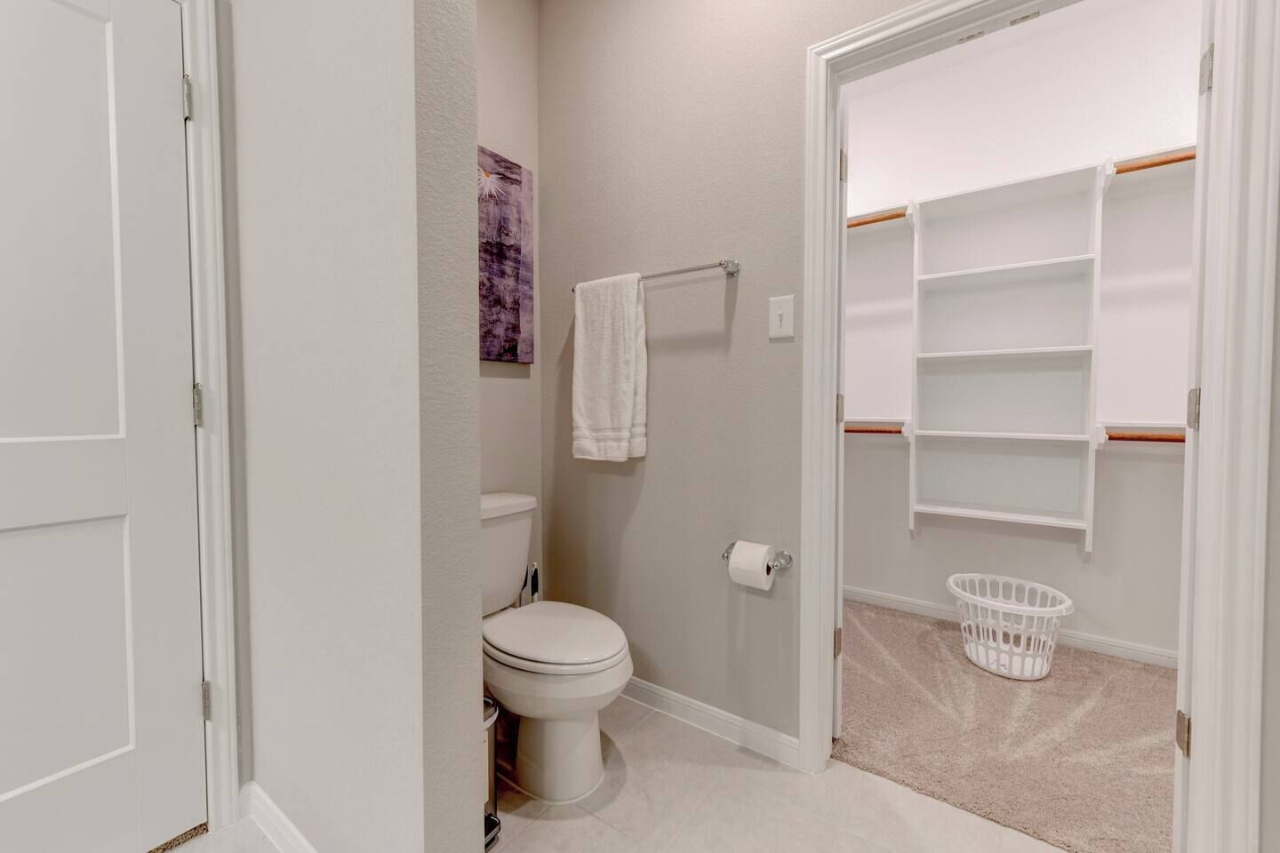 Ein Badezimmer mit Toilette, Handtuchhalter, Korb und Regaleinheit.