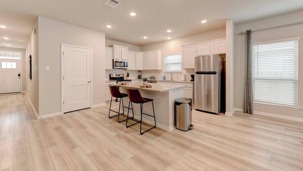 A modern kitchen with a central island, bar stools, stainless steel appliances, and a trash can. - Spacious Haven for Workers in South Temple (Temple)