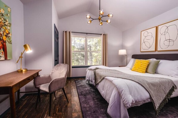 Un dormitorio con cama, escritorio, silla, ventana y candelabro.