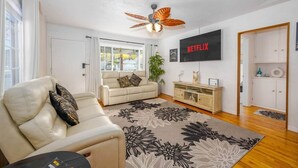 Ein Wohnzimmer mit einer Couch, einem Couchtisch, einem Deckenventilator, einem Fernseher und einem Schrank.