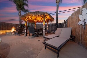 An outdoor patio with a thatched-roof gazebo, lounge chairs, and a fire pit. - Private Pool & Spa 3BR Sleeps 8 Resort-style Retreat Near San Diego (Lakeside)
