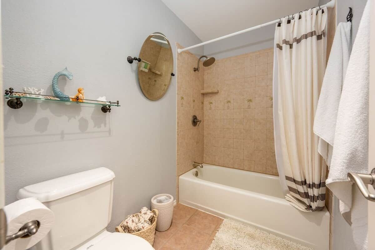 Un baño con inodoro, ducha, bañera, espejo y toallero.