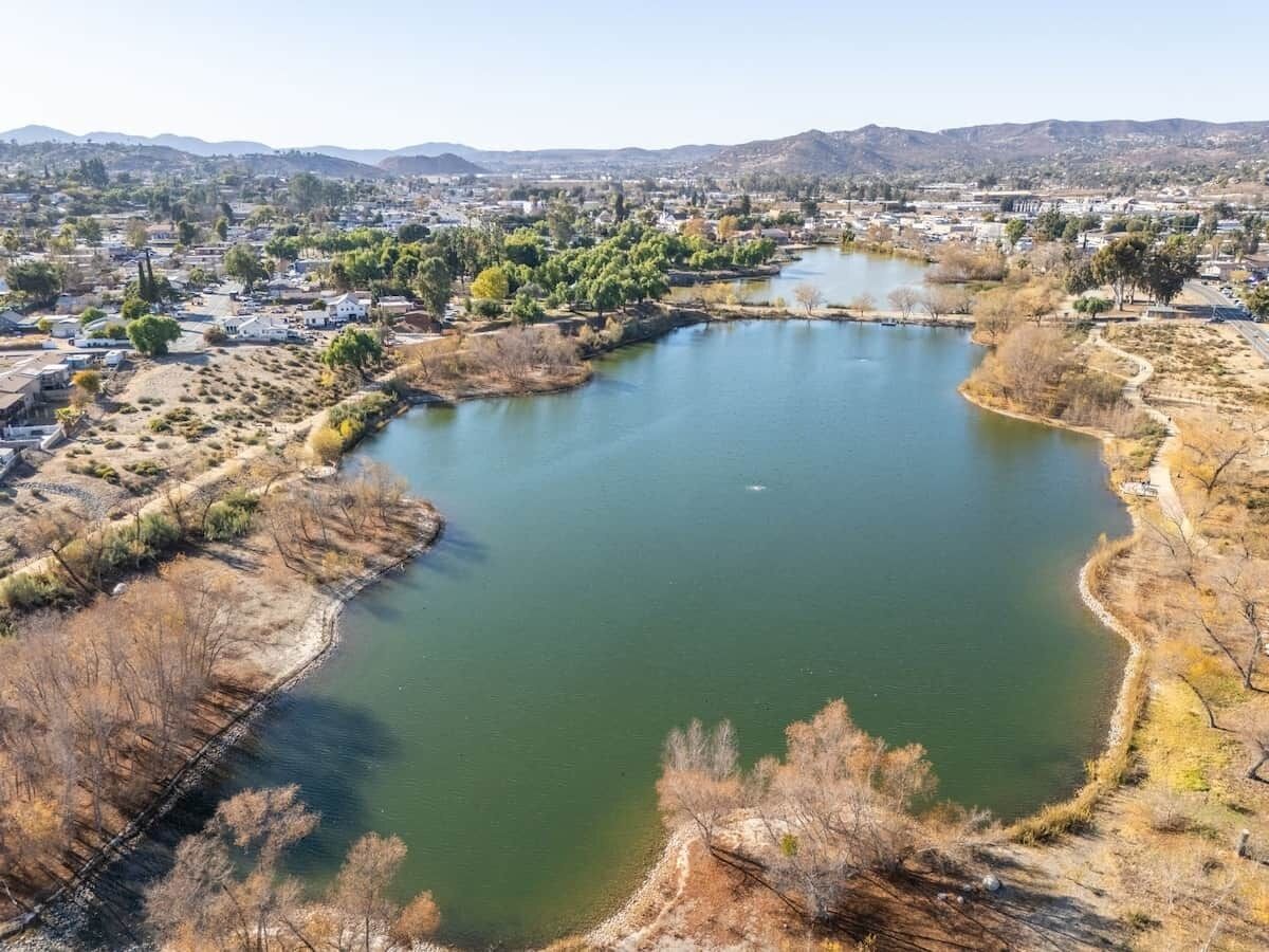 Vista aèria d'un llac envoltat de vegetació seca i una població al fons.
