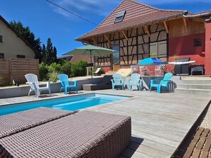 En swimmingpool med liggestole og grillområde.