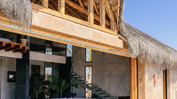Una villa moderna con piscina, terrazza in legno e tetto di paglia.