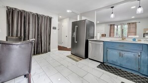 A modern kitchen with a stainless steel refrigerator, blue cabinets, and a white countertop. - Charming 3-bedroom bungalow with WiFi in Bham, 12 mins from UAB. (Birmingham)