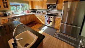 A kitchen with wooden cabinets, a stainless steel refrigerator, a stove, and a microwave.