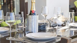 A dining table set with plates, glasses, and a bottle of champagne. - Villa with 2 bedrooms, big porch and amazing ocean view
 (Kralendijk)