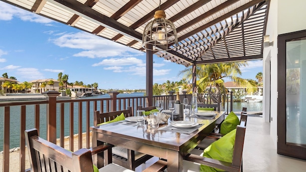 A dining area with a view of the water, wooden furniture, and a pergola structure. - Villa with 2 bedrooms, big porch and amazing ocean view
 (Kralendijk)