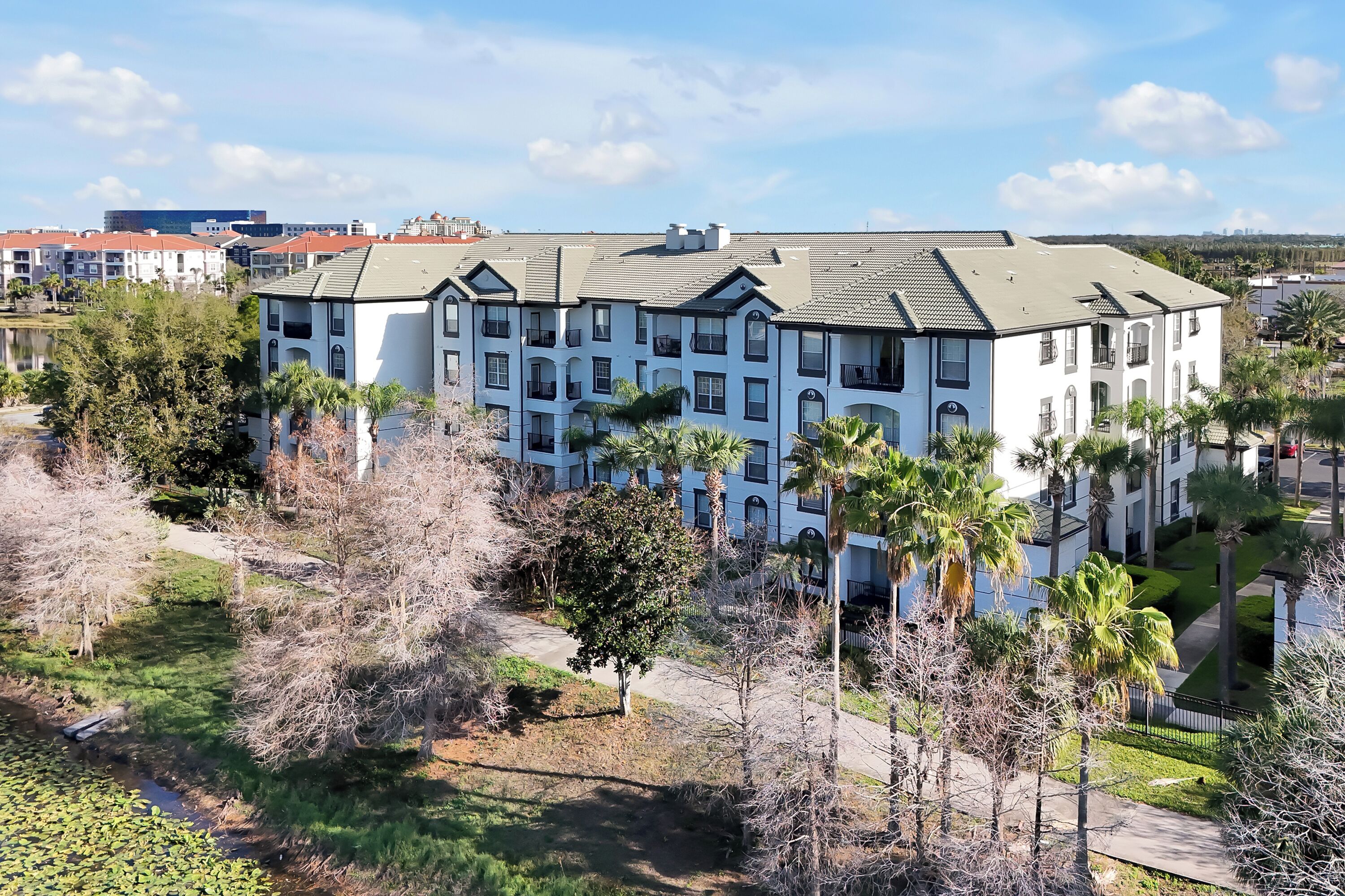 A multi-story building with a symmetrical facade, multiple balconies, and a central courtyard with palm trees.