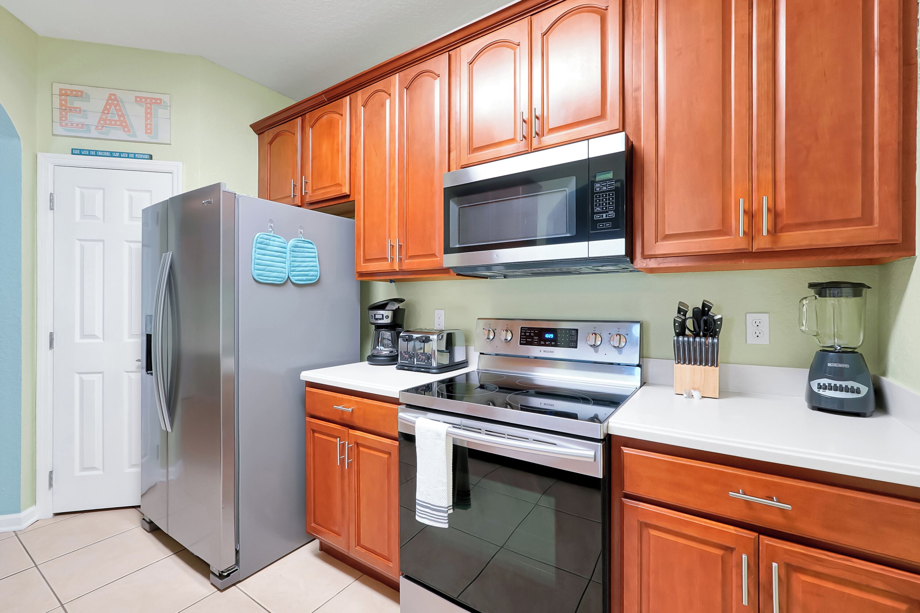 A kitchen with wooden cabinets, stainless steel appliances, and a white countertop.