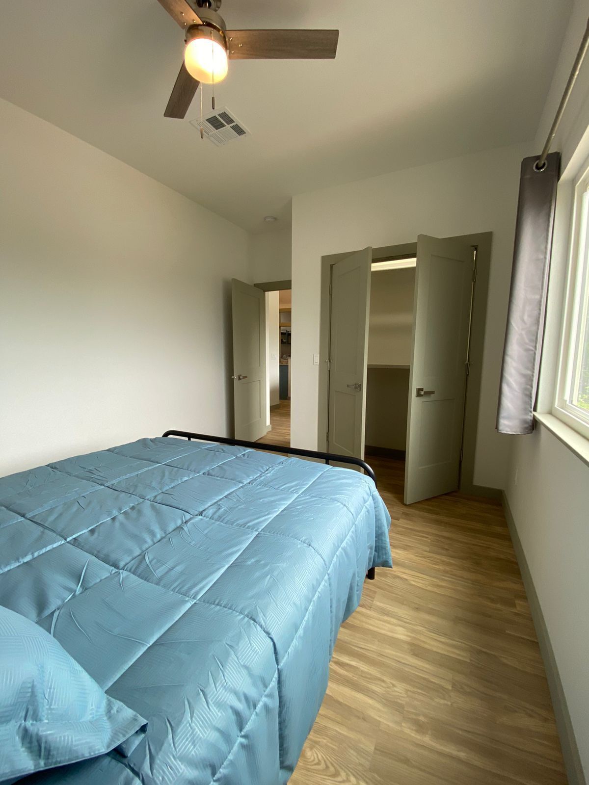 Un dormitorio con cama, ventilador de techo y ventana.
