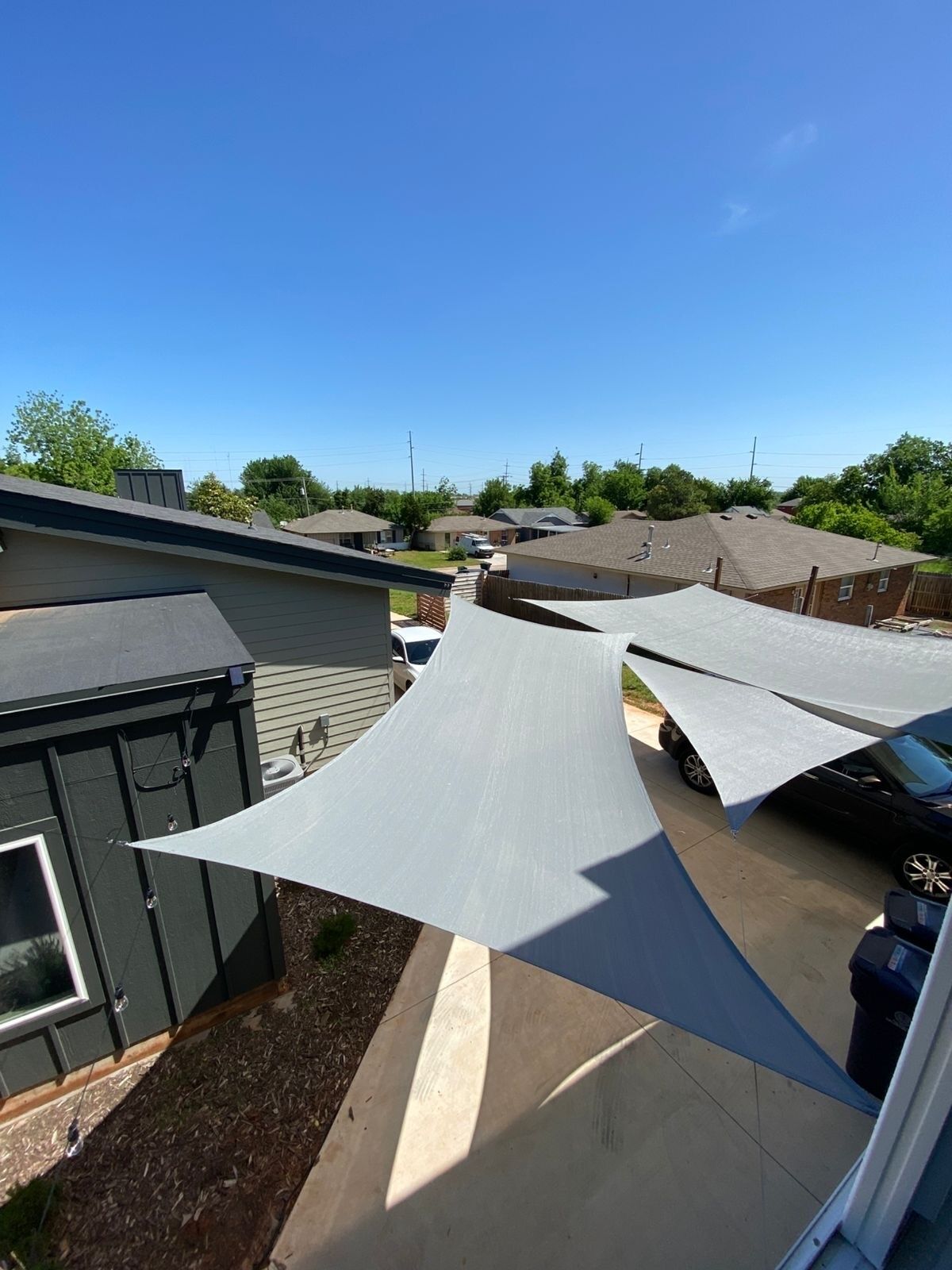 A residential area with multiple houses, a clear sky, and a playground structure with a shaded area.