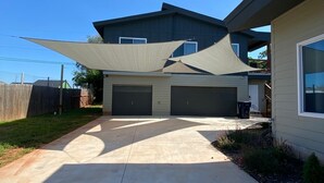 A residential house with a garage, a covered driveway, and a large shade sail.