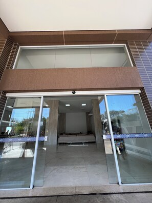 A modern building entrance with a glass door, a ramp leading to a seating area, and a tiled floor. - DiRoma Spazzio - Direto com o Grupo DiRoma - acesso ao Acqua Park com café da manhã (Caldas Novas)