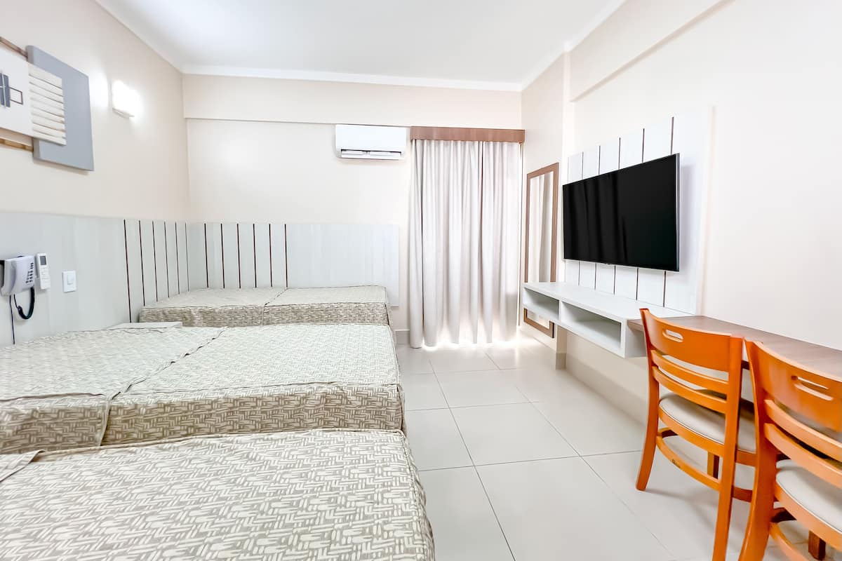 Ein Hotelzimmer mit zwei Betten, einem Fernseher, einem Schreibtisch und einem Sessel.