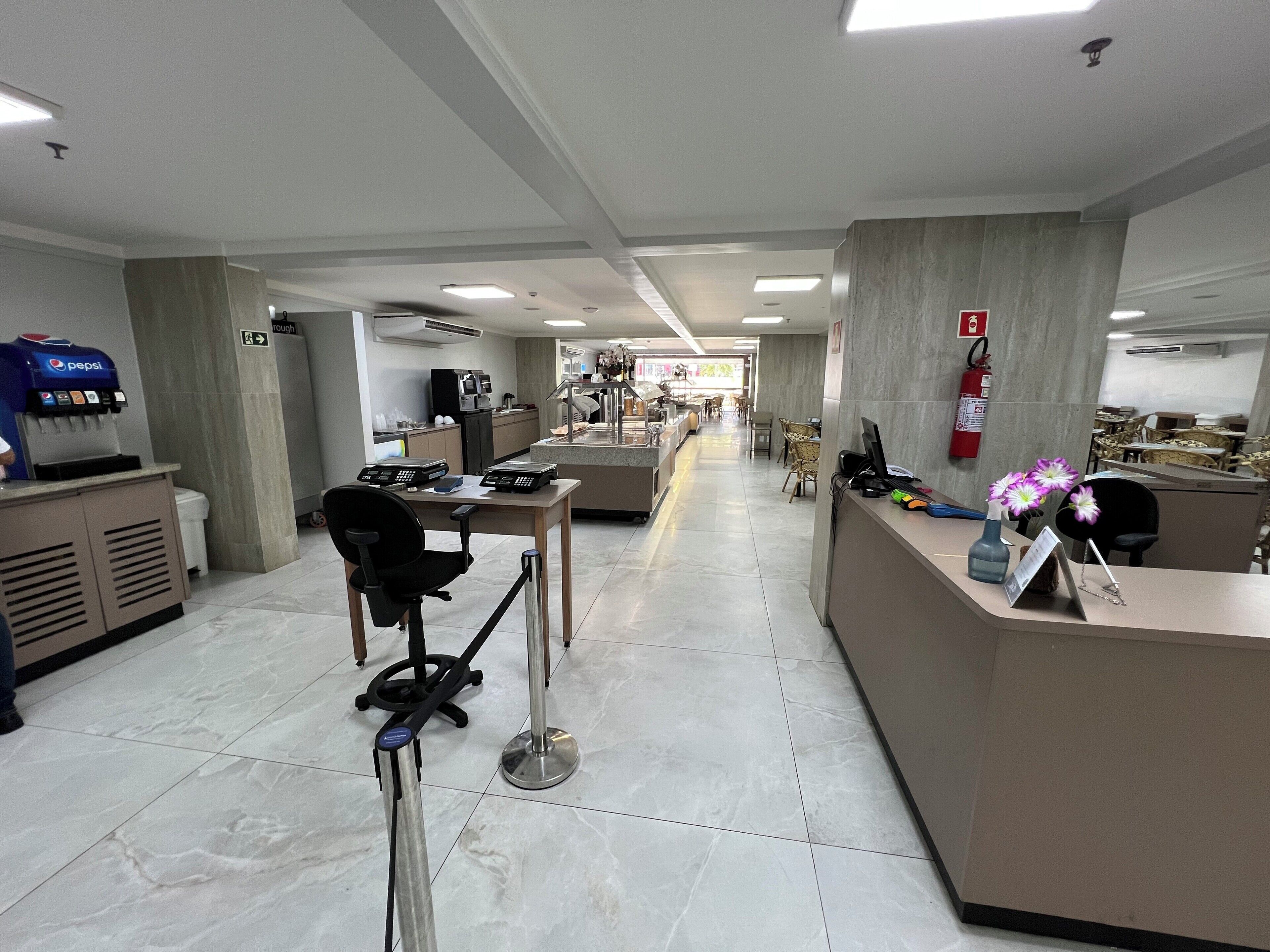 Un hall d’hôtel comprenant un comptoir d’accueil, un espace salon et un distributeur automatique de boissons Pepsi.
