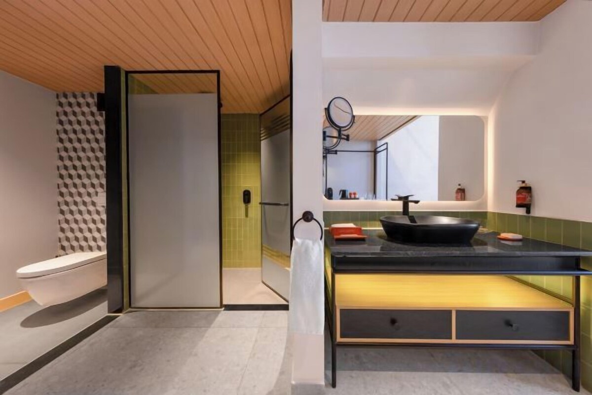 A modern bathroom with a toilet, a shower, and a sink with a mirror.