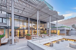 A modern outdoor seating area with a covered patio, large windows, and contemporary lighting fixtures. - Hyatt Centric Cairo West (6th of October City)