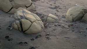 Une plage avec de gros rochers et des empreintes de pas dans le sable.