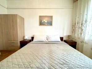 Ein Hotelzimmer mit einem großen Bett, einem Nachttisch mit Lampe, einem Kleiderschrank und einem Bild an der Wand.