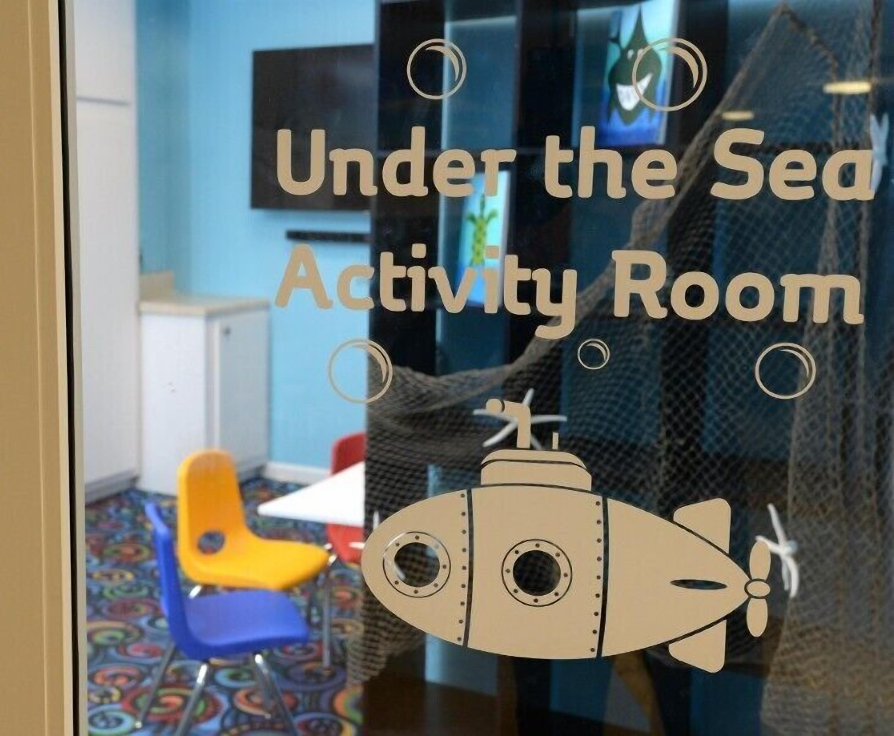 Una habitación con ventanal que muestra un submarino y el texto 'Under the Sea Activity Room'.