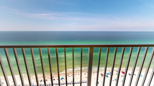 A balcony with a view of a beach and the ocean.