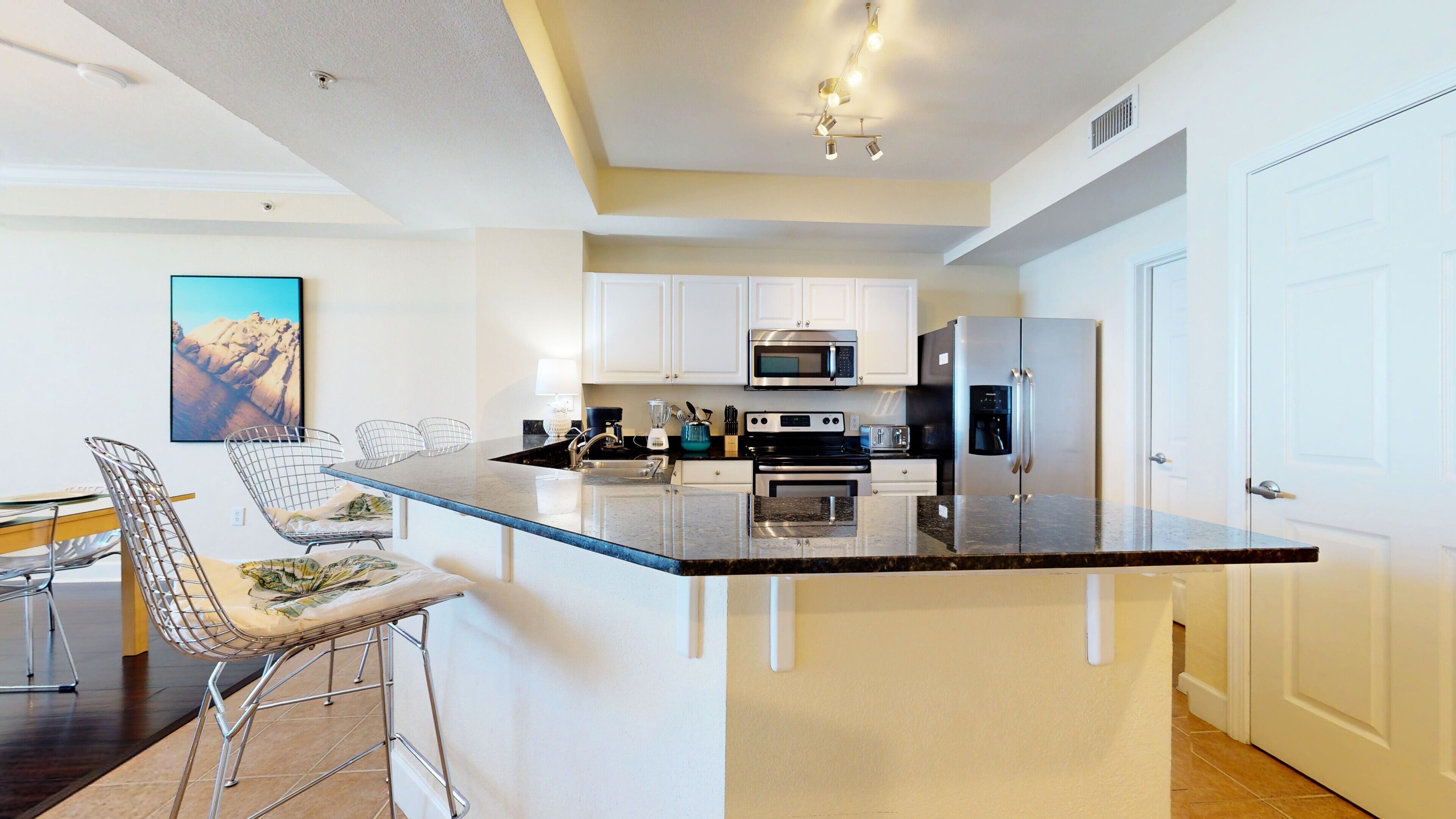A modern kitchen with white cabinets, stainless steel appliances, and a central island with bar stools.