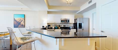 A modern kitchen with white cabinets, stainless steel appliances, and a central island with bar stools.