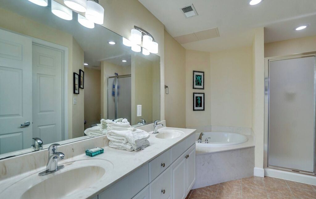 A modern bathroom with two sinks, a large mirror, and a walk-in shower.