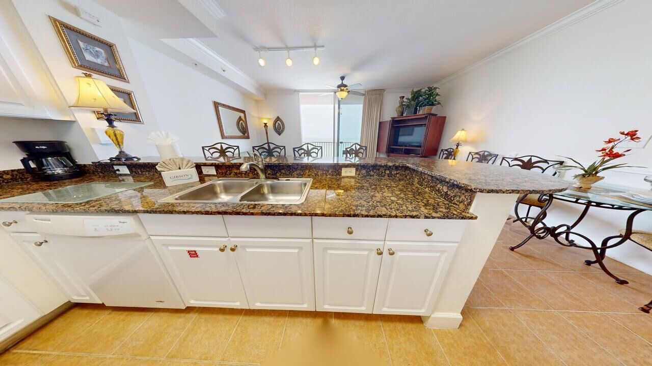 Une cuisine dotée de plans de travail en granit, de meubles blancs et d’un coin repas avec une table et des chaises.