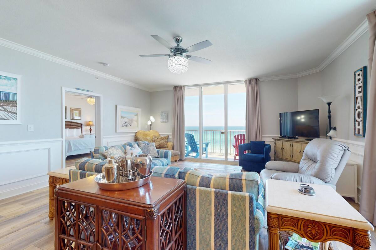 Ein geräumiges Wohnzimmer mit Balkon, Deckenventilator und Fernseher.