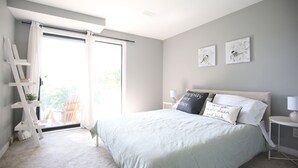 Ein Schlafzimmer mit Bett, einer Leiter, einem Stuhl und Blick ins Freie.