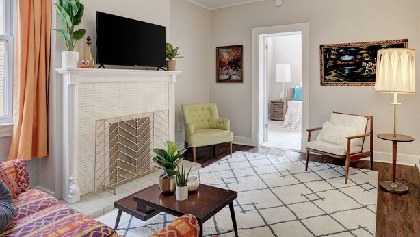 A living room with a fireplace, a television, and two chairs. - Fun Retro Apartment on Quiet Dead End Street Near Stage AE & Acrisure Stadium (Pittsburgh)
