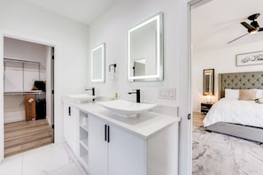 A modern bathroom with two sinks, a mirror, and a ceiling fan.