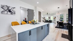 A modern kitchen with a central island, grey cabinets, and a white countertop.