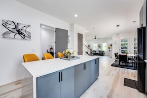 A modern kitchen with a central island, grey cabinets, and a white countertop.