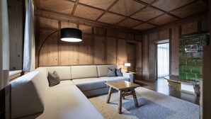 Een kamer met houten lambrisering, een bank, een tafel en een lamp.