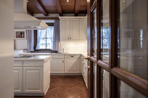A kitchen with white cabinets, a tiled floor, and a window with curtains. - Apartment 'Appartamento Stube' with Mountain View, Private Terrace and Wi-Fi (Ortisei)