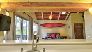 A kitchen with two stainless steel sinks, a wooden ceiling, and a red surfboard on the wall. - Air Conditioned Upstairs Condo with full kitchen, pool, wifi, walk to beach. (Princeville)