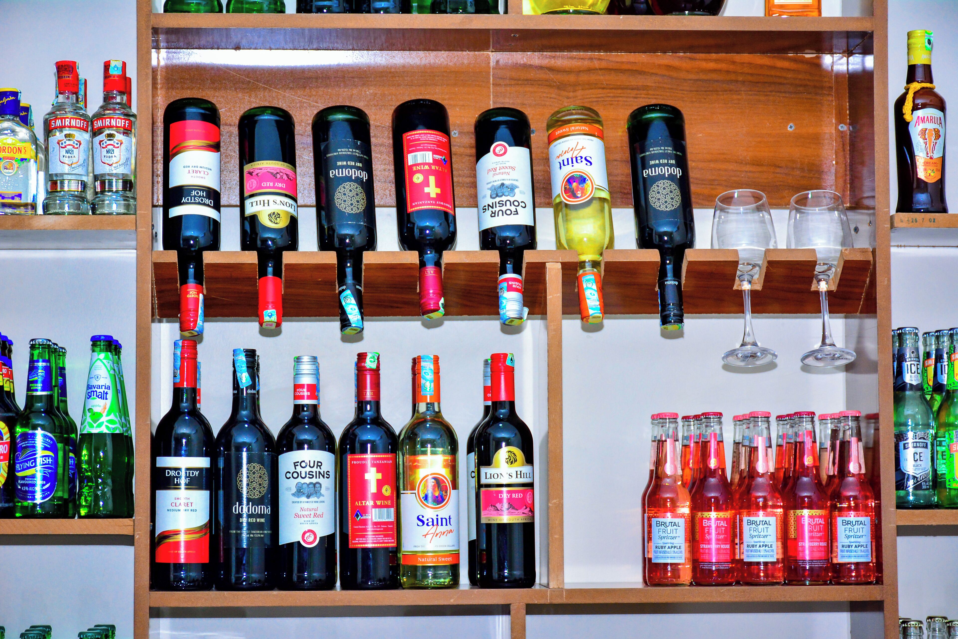 A variety of liquor bottles on shelves, including vodka, wine, and fruit spritzers.
