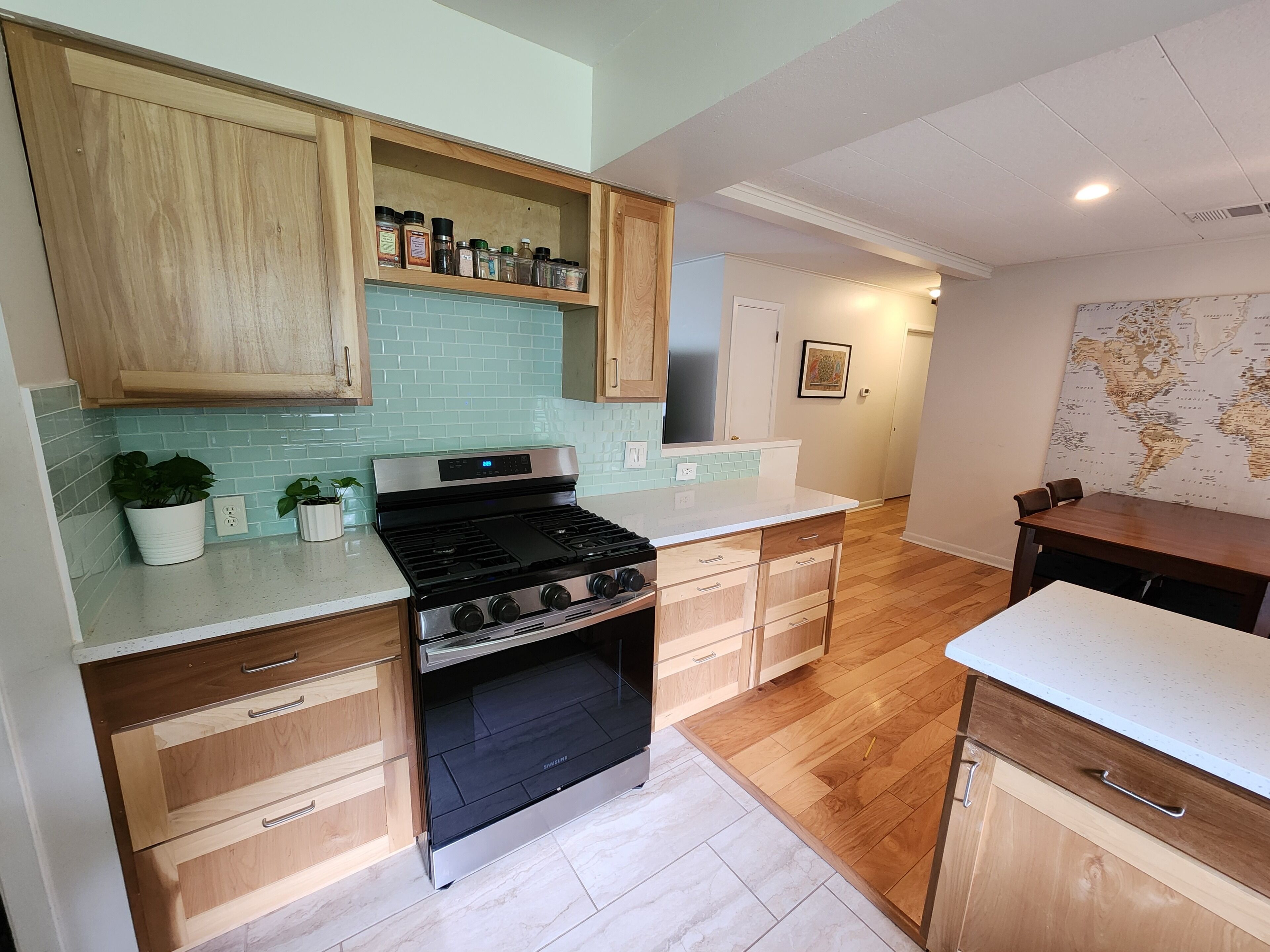 A modern kitchen with a stainless steel stove, wooden cabinets, and a light blue tiled backsplash.