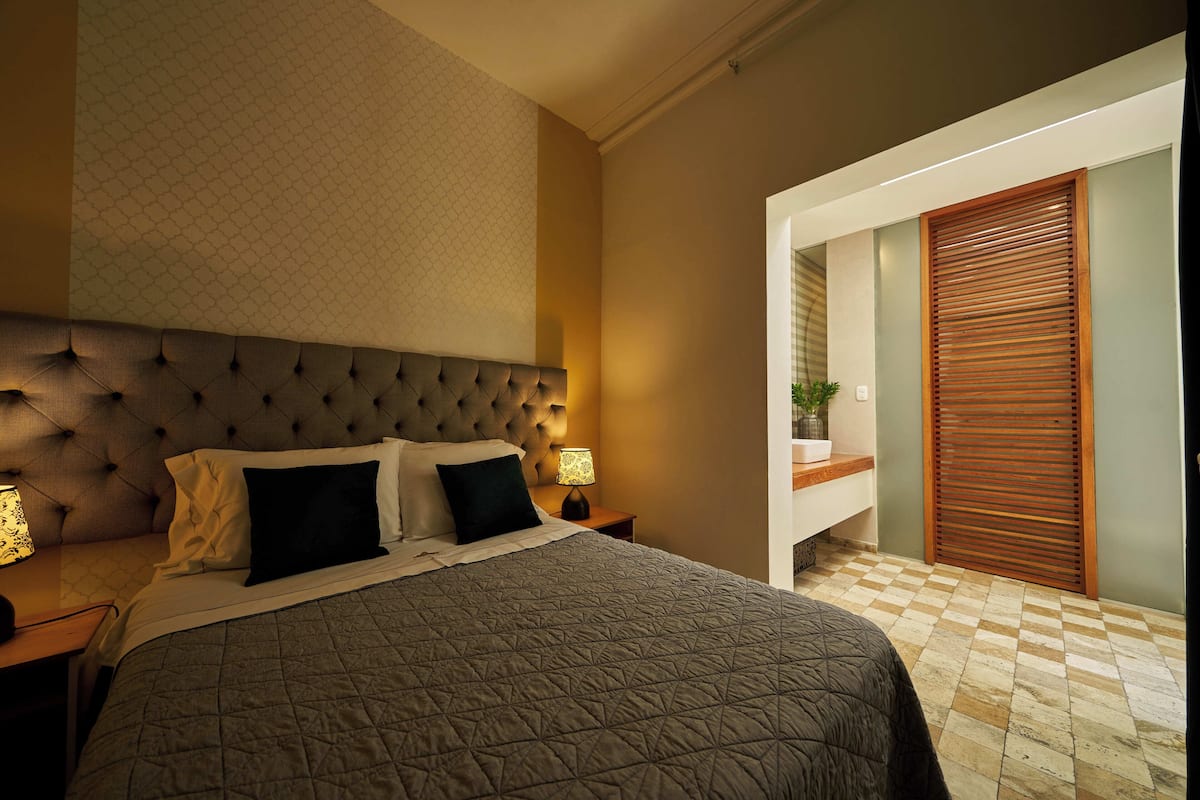 A neatly made bed with a quilted cover, a tufted headboard, and two bedside lamps.