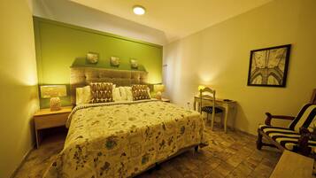 A bedroom with a large bed, a nightstand, a chair, and a small table.