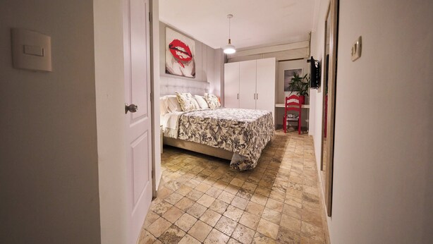 A bedroom with a bed, a wardrobe, a red chair, and a wall-mounted artwork. - PUCLLANA  B&B BOUTIQUE (Lima)