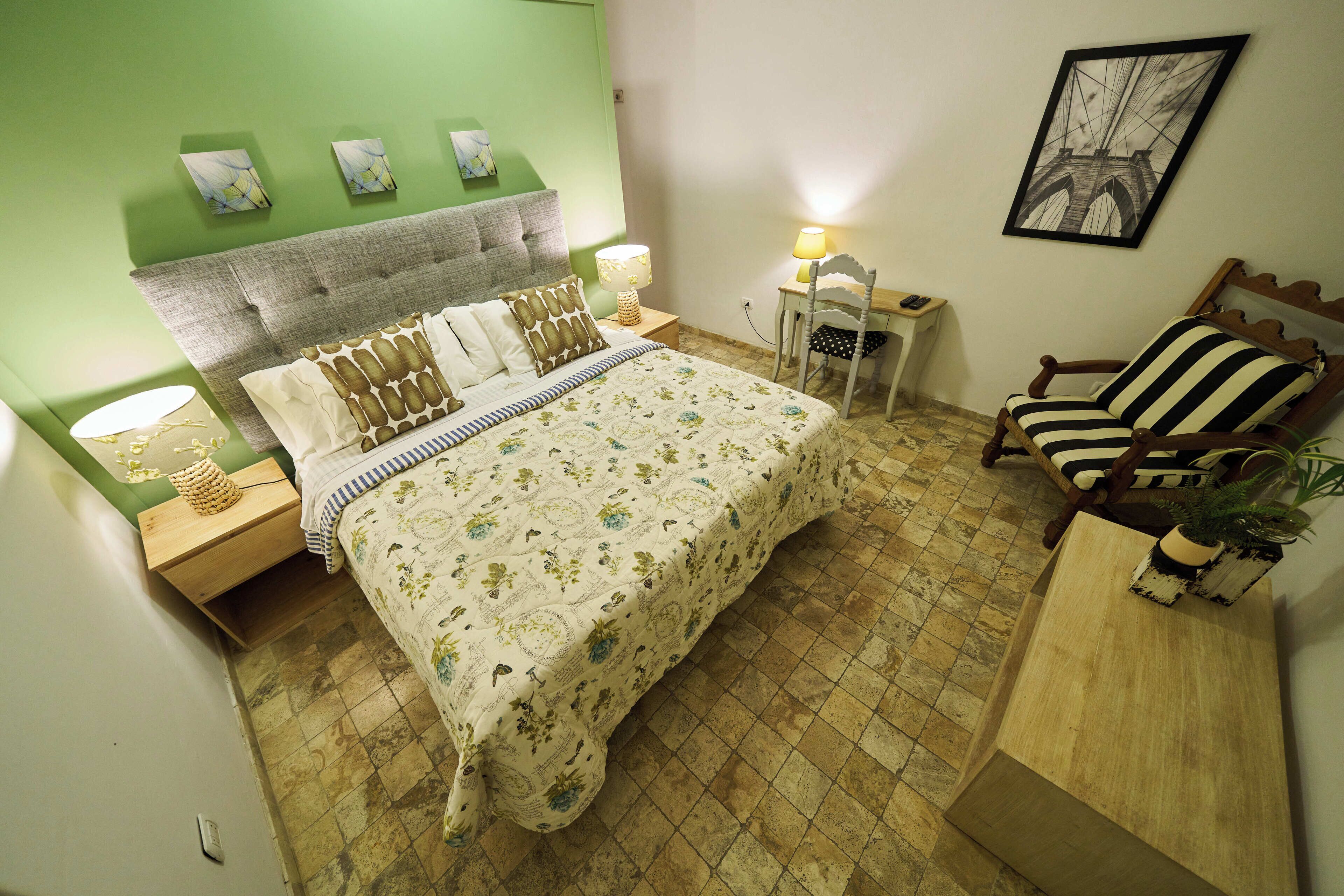 A bedroom with a bed, nightstands, a chair, and a small table.