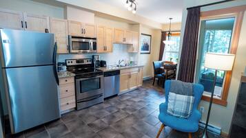 A modern kitchen with stainless steel appliances, wooden cabinets, and a checkered floor.
