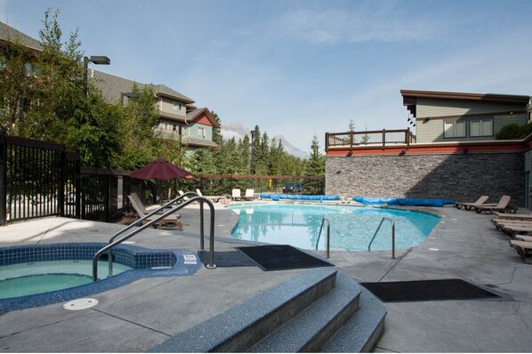 Relax by the pool surrounded by a stone wall and lounge chairs.
